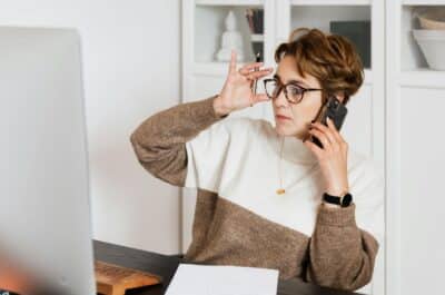 Modern woman talking on mobile in front of computer
